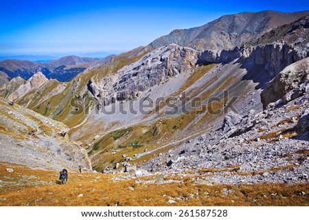 Group of trekking tourists ascent to the mountain pass during their hike in magnificent and stunning Caucasus mountains at autumn, Arhiz region, Abishira-Ahuba range, Karachay-Cherkessia, Russia