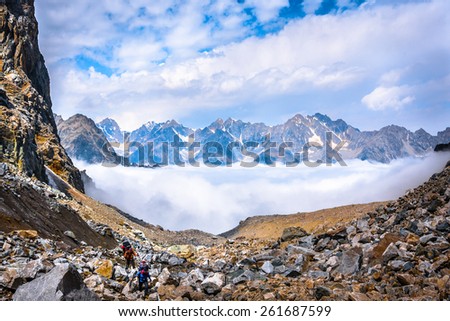 Climbers move above the clouds on background of beautiful mountains. Picture was taken during trekking hike in the majestic and stunning mountains of Caucasia, Bezengi region,Kabardino-Balkaria,Russia