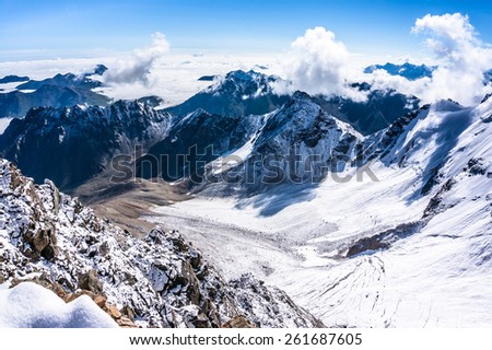View from the bird\'s-eye over the mountains and clouds from Uku pass.Glacier below. Picture was taken during trekking hike in the beautiful Caucasus mountains, Bezengi region,Kabardino-Balkaria,Russia