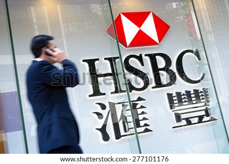 Hong Kong, Hong Kong SAR -November 17, 2014: Motion blured business man passing by an HSBC Bank sign in Hong Kong. HSBC Holdings plc  is the world\'s third largest bank by assets.