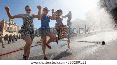 KRAKOW, POLAND - JUNE 11, 2014: Youth seeking escape from the summer heat in Main Square in Cracow, Poland