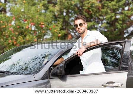 businessman gets into his car to go to work. fashionable boy gets into his car parked in the garden.
