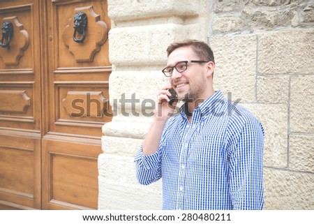 fashionable boy talking on the phone with a client to work on a background of red rock. stylish man speaks on phone with his girlfriend smiling.