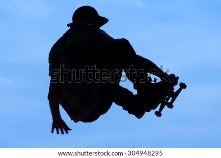 silhouette of a skater in the air during a trick , on a background of blue sky. man skate in a day dedicated to training on the table. day skate contests.