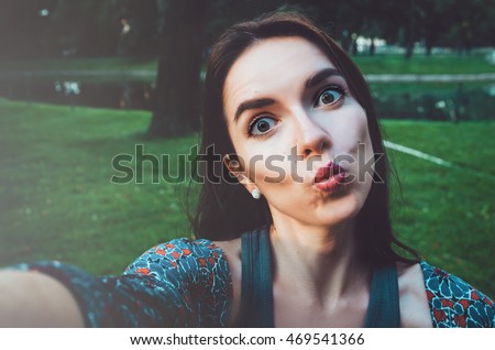 Pretty student girl taking photo selfie and making duck face. Female sending kisses, enjoying self portrait. Herself Instagram concept. Lifestyle portrait of happy woman looking on camera phone.