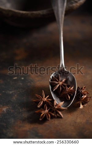 Star anise inside and outside of metal vintage spoon with coffee dust around