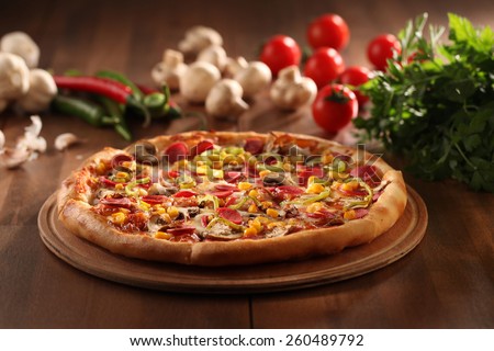 whole italian pizza on wood table with ingredients
