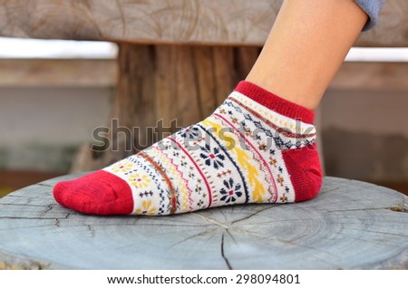 Women wearing socks put a foot on a wooden chair.