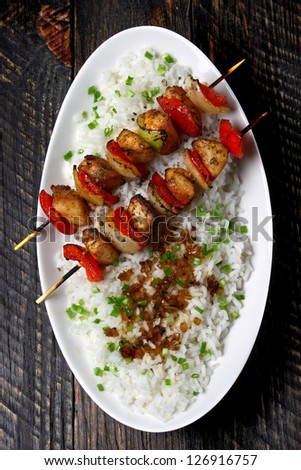 Chicken skewers with rice on a wooden table
