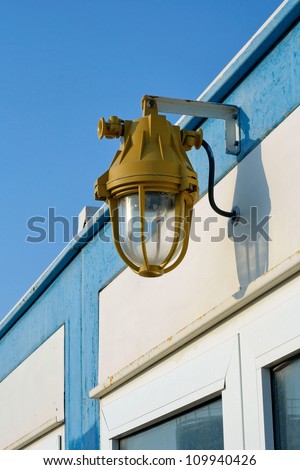 Explosion proof lighting with a heavy protective metal casing mounted on the exterior wall of a building