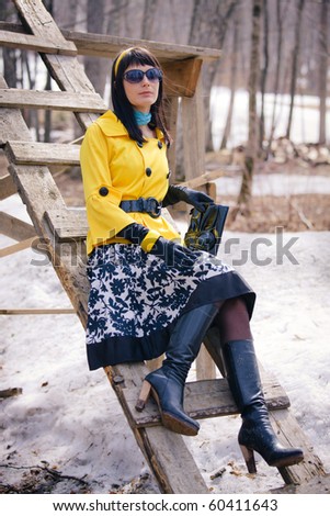 glamorous young woman posing on a ski holiday base, in early spring when the snow began to turn into a mud