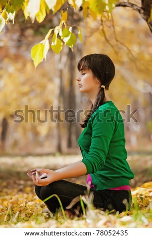 beautiful girl with dark hair, yoga in the yellow autumn leaves