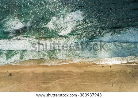 Aerial view of ocean beach. Sand beach and sea view from above. Beach aerial view of ocean water and sand shore. Aerial shot of beach emphasizing the scale of people and nature