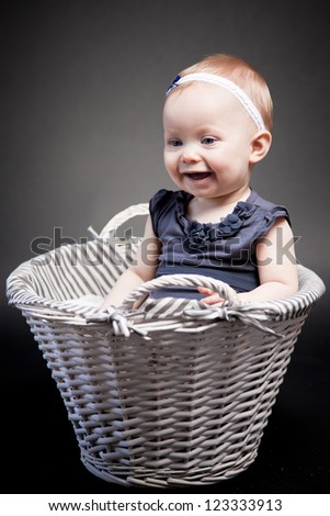 Baby girl posing in a vintage basket. The look at her face expresses her exploration of the world.