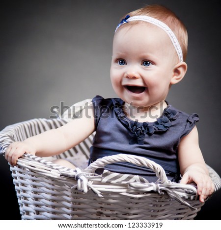 Baby girl posing in a vintage basket. The look at her face expresses her exploration of the world.