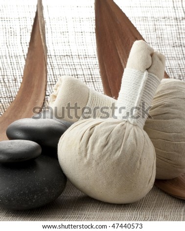 Herbal massage balls with some zen stones in the background presented on dried banana leafs