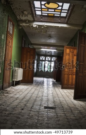 A grungy looking hallway, with open wooden doors. Shot taken at an old abandoned building, build in the beginning of 1900.
