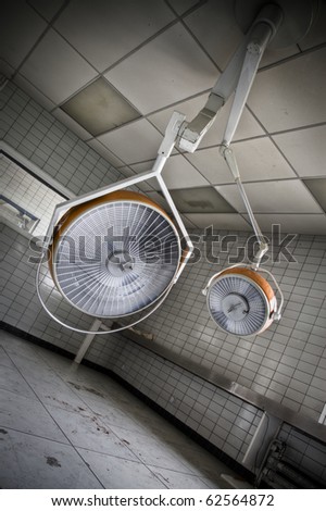 A creepy surgery room with only the surgical lamps hanging to let time steal there beauty