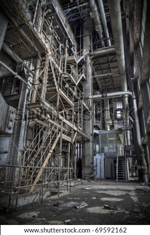 The interior of an old abandoned machine hall, with the control room in front and the staircase to reach the upper deck on the left.