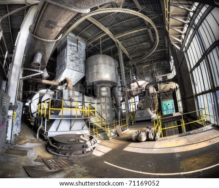 A panorama of the interior of an abandoned power plant. Light slides down the floor creating a moody image.