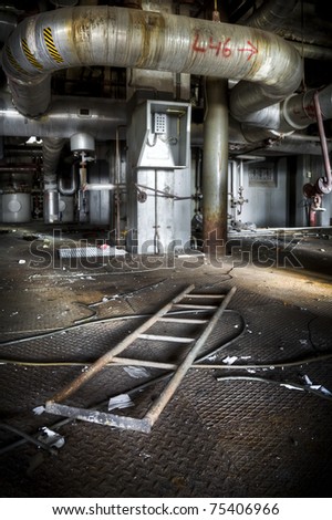 A ladder laying in front of an emergency call station at an abandoned industrial area. Looks like something happened and everyone had to leave the building.
