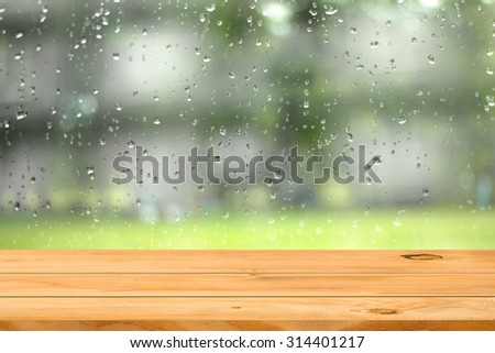 Empty wooden table over water drop on window garden background. Ready for product display montage.