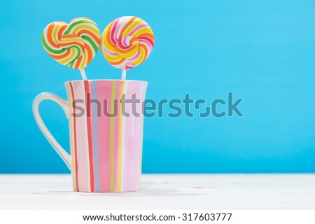 colorful round candy and heart candy in a vertical stripes cup pastel color on wooden table with copy space concept love, romance