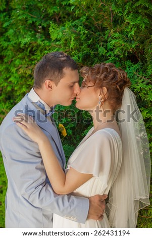 Portrait of kissing newlyweds.The groom kisses his bride\
while her eyes closed.Love relationship.wedding day