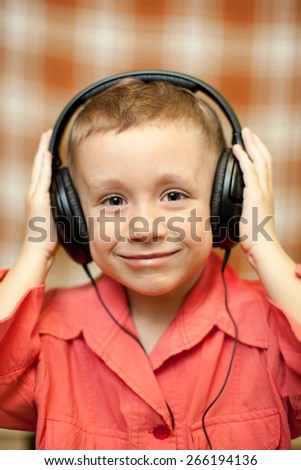 boy in red rkbashke listening to music through headphones, smiling boy,Close-up of a child listening to music with headphones