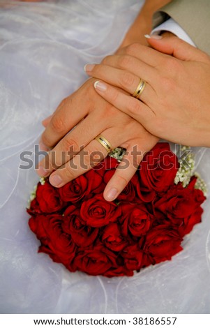 Married couple hands at wedding ceremony and rose bouquet