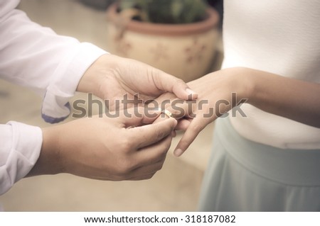 Man holding hand of girlfriend and give engagement ring on her finger with soft light orange tone and grain. concept vintage light smooth tone