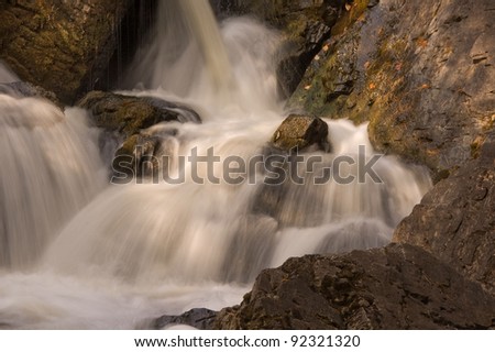 Photograph of the intimacy of a north woods waterfall with the rushing water crashing down over moss covered rocks.
