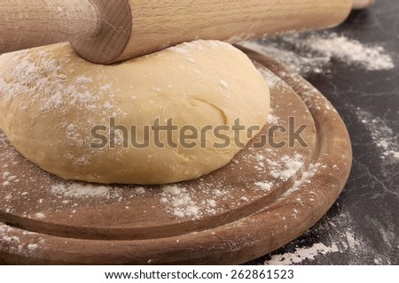 Freshly prepared dough and rolling pin on a wooden board. Selective focus