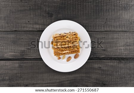 Cake slice with nut on plate, on wooden table, top view.