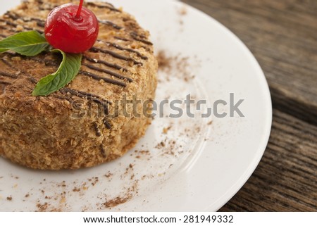 Layered cake with nut and cinnamon on plate, on wooden table, dark background. Selective focus.