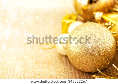 Golden Christmas decorations on shiny background with copy space for text. Christmas background or greeting card. Selective focus.