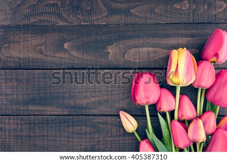 Frame of tulips on dark rustic wooden background. Spring flowers. Spring background. Valentine\'s Day and Mother\'s Day background. Top view.