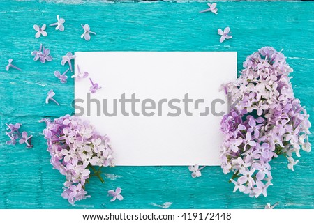 Lilac blossom on turquoise rustic wooden background with empty card for greeting message. Mother\'s Day and spring background concept. Holiday mock up. Top view.