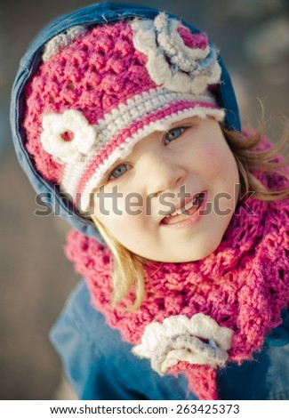 A happy little girl in a pink woolly hat and scarf