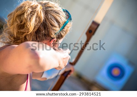 Young woman aiming with a bow