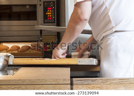 A man baking cakes and other stuff of sweets in front of an oven