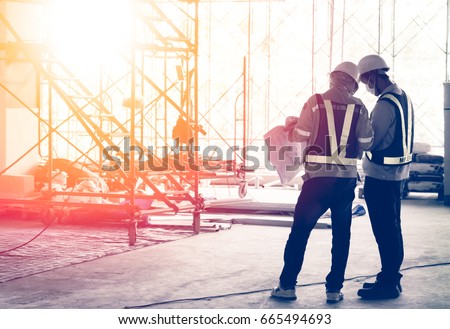 Silhouette engineer in safety protective equipment standing orders for construction crews to work at building construction site. It\'s a key successfully for business, successful concept
