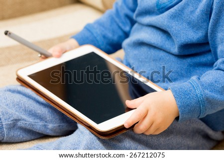 Baby hands holding tablet pc, baby sitting and playing with tablet pc.