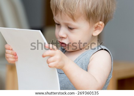 Baby, little boy holding clear sheet of paper.