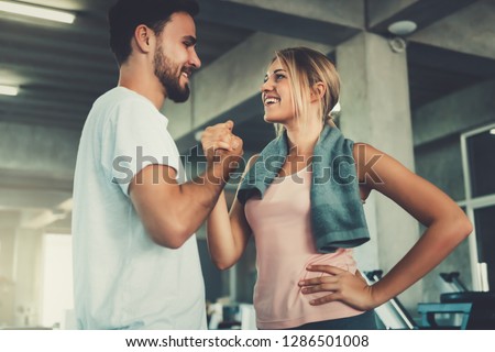 Attractive young couple handshaking after workout in fitness gym., Portrait of man and woman couple love are working out training together., Couple fitness and healthy concept.