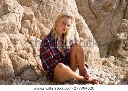 Sexy Girl in flannel shirt on the rocky beach.