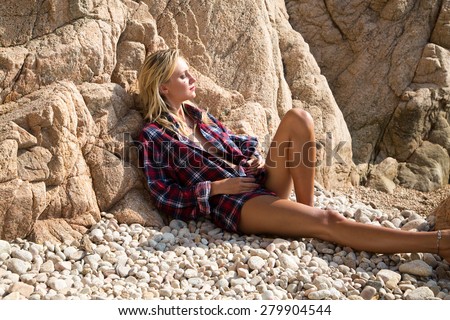 Sexy Girl in flannel shirt on the rocky beach.