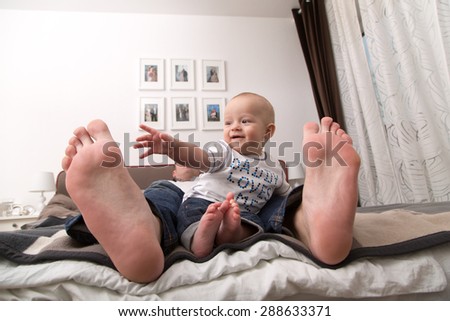 Child playing with the big toe of his father.