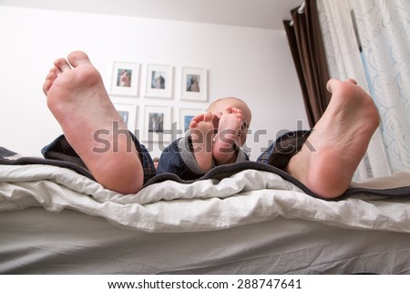 Child playing with the big toe of his father.