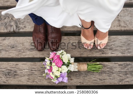 Close up of bride's and groom's feet and wedding bouquet of flowers